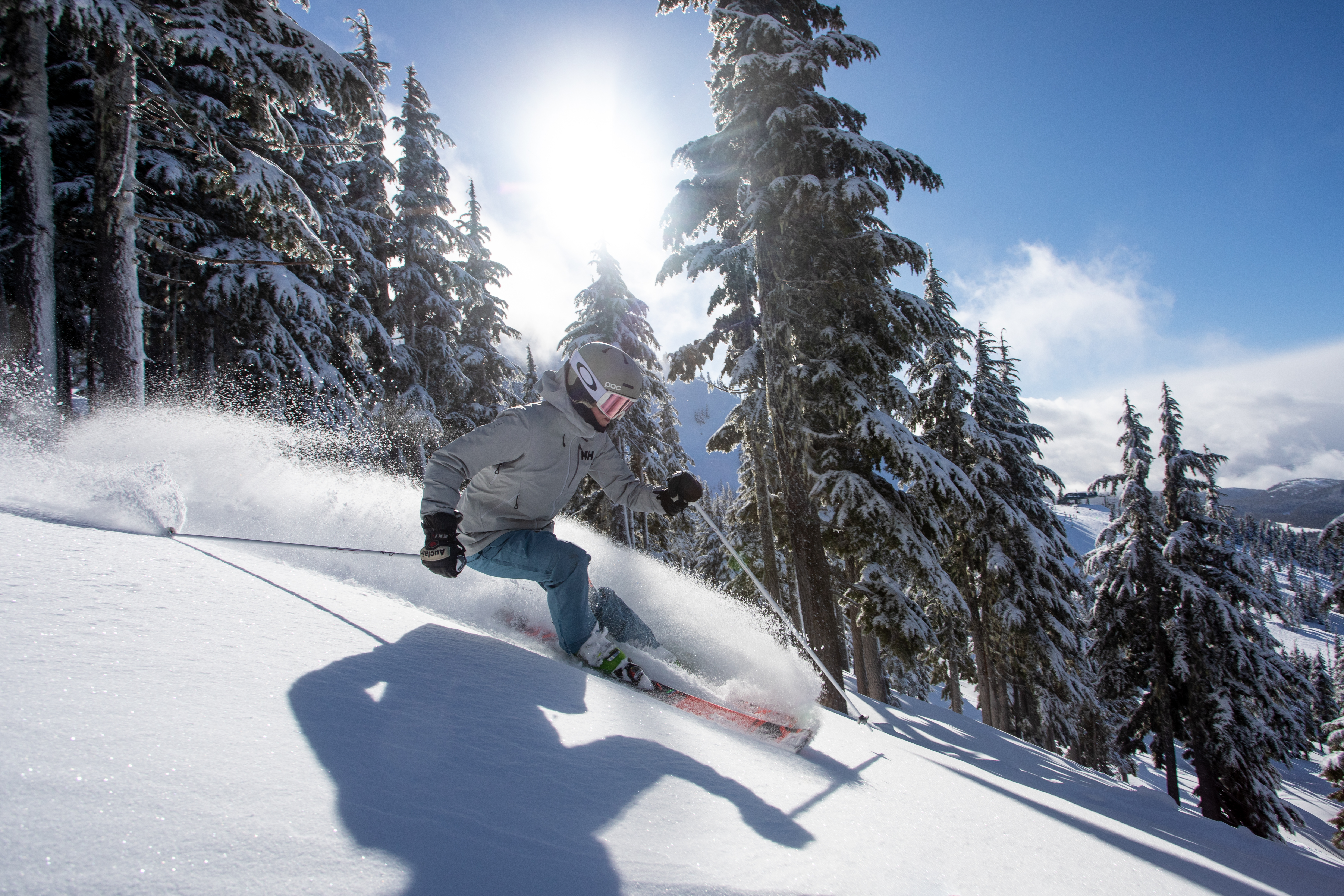 A skier in a grey jacket skiing down a mountain at Mount Washington Resort, British Columbia.